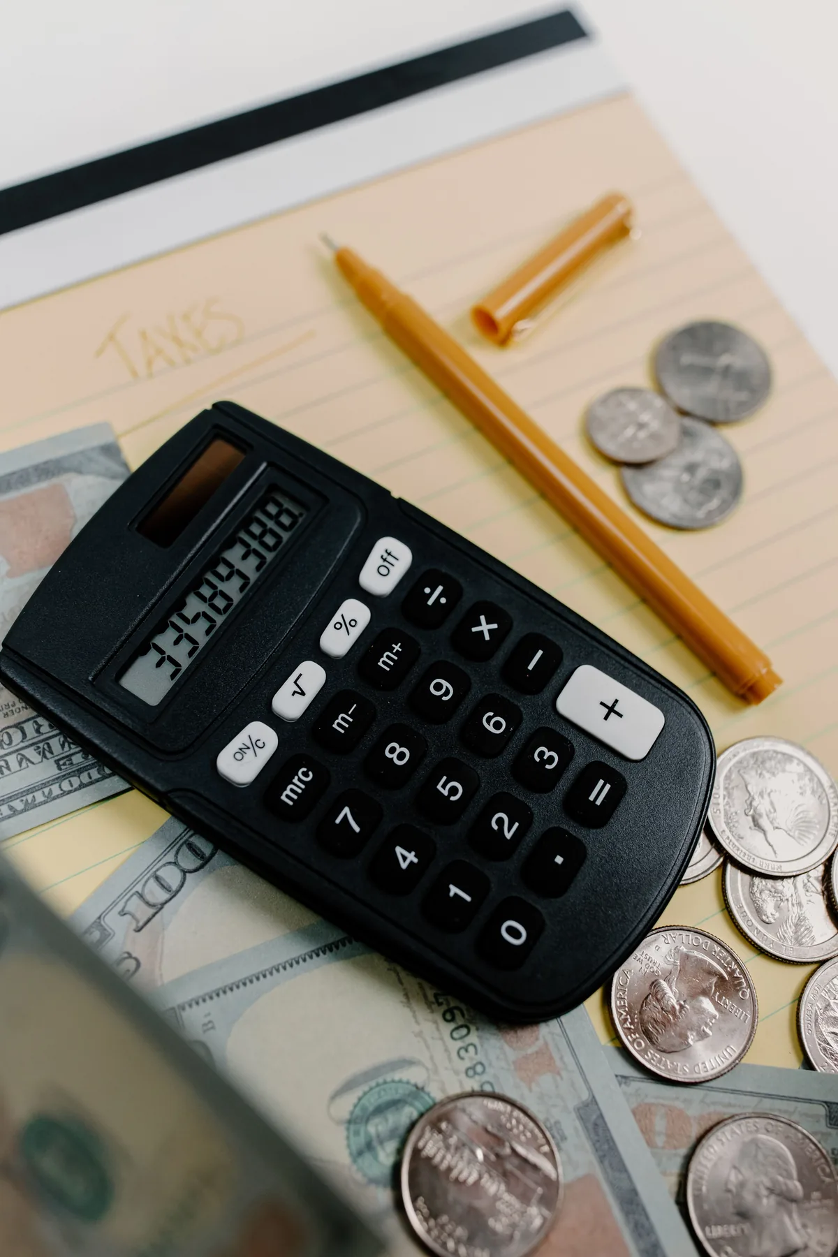 A calculator, money and notes used for financial calculations